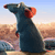 A pixelated blue rodent stands upright on a sandy background with a light blue sky, its red ears and nose visible.