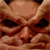Static pixelated image of a stylized human face with dark eyes, nose, and mouth against a brown-toned background.