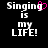 Black background with white pixelated text "Singing is my LIFE!" and a pink heart symbol replacing the 'g' in "Singing" on the left side.