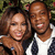 Two people pose closely together in a pixelated image with blurred background foliage.