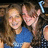 Two people with long brown hair pose closely together; one wears a blue shirt, the other dark clothing. Text "Lauren" and "Hugs" appears in blue pixelated font on black background.