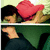 A person with dark hair holds a red pillow against their face, alternating between green and light-colored backgrounds.