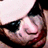 A pixelated close-up of a person with closed eyes, dark hair, and light skin wearing a red garment against a bright background.