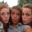 Three people pose together in a pixelated outdoor photo with a light blue background containing red text.