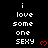 Pixelated text reads 'i love some one SEXY' with red heart symbols on black background, arranged in repeating vertical