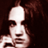 Pixelated static icon of a person with light skin tone, dark hair, and a white lampshade-like headpiece against a dark brown background.