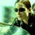 Pixelated static image of a person with short brown hair wearing dark sunglasses and a black top, positioned against a blurred greenish background.