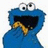 Blue cartoon character with large eyes and open mouth holding a cookie, blue text reading WANT COOKIES on black background.