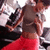 A person in a gray crop top and red pants stands with arms crossed, viewed from the side against a blurred background.