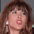 Static close-up of a woman's face with brown hair, red lips, and visible teeth in a pixelated 50x50 icon format.