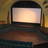Pixelated image of a rectangular screen with a gradient light display, framed by dark borders and surrounded by blurred warm-toned background elements.