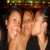 Three people in a group pose with one person kissing another on the cheek, visible