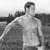 Black-and-white photograph of a shirtless man in a field with text overlays in cyan block letters.