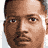 Static image with red text on black background, featuring a partial portrait of a person in the top-left corner and a circular 'TNT' logo in the bottom-right.