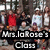 Group photograph of children and adults in a classroom with overlaid text "Mrs.JaRose's Class" on black rectangular background.