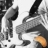 Pixelated grayscale image of a stylized figure with outstretched arms and a small orange element near the bottom right.