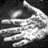 A grayscale pixelated image of a hand with fingers extended, palm facing forward against a dark background.