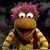 A pixelated contact sheet showing two frames of a Fraggle Rock character with purple hair and brown skin on the left, next to green text reading "Original Icons .com" on a dark background.