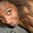 Pixelated close-up of a person with light brown hair lying down, wearing dark clothing and a gray garment beneath.