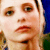 Pixelated close-up of a person's face showing eyes, nose, mouth, and partial hair against blue and green background elements.