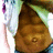 Pixelated image of a figure with light-colored hair and purple accents, wearing a brown garment against a greenish background.