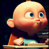 Bald animated character with large blue eyes and green food on lips, wearing orange and blue clothing, seated at a table with a plate.
