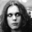 Black-and-white pixelated portrait of a person with long dark hair, neutral expression, and visible facial features including eyes, nose, and mouth.