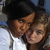 Two people in close proximity, one with dark hair wearing a white shirt and the other with lighter brown hair.