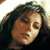 Pixelated static image of a person with long dark hair and light skin tone, cropped to show upper face and shoulders against a bright background.