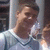 Pixelated static image of a person with brown hair wearing a light-colored shirt and dark necklace, positioned against a blurred background.