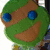 Green cartoon turtle head with blue eyes and brown patches, next to bright green text on pink background.