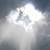 Pixelated static image of a bright white cloud-like shape against a dark blue-gray background with light gray and white cloud formations.