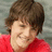 Pixelated image of a person with brown hair in red clothing on left, pink background with text and symbols on right.