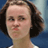Static 48x48 pixel icon showing a person with short brown hair against a blue background, wearing a white top with visible collar and shoulder details.