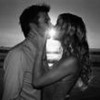 Black-and-white image of two people kissing at sunset, with a bright light source behind them creating a silhouette effect.