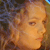 Pixelated close-up of a person's face with light brown hair, showing partial facial features against a blurred background.