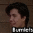 Pixelated image of a person with dark hair and light skin, profile view facing left, against a brown textured background with white text reading "Bumlets" at the bottom.
