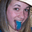 A person with light brown hair and a white cap sticks out a blue tongue in three showing slight head movement