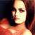 Pixelated close-up of a person with long brown hair, wearing a red garment, against a dark background.
