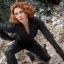 Static 64x64 pixel icon showing a person with red hair in black clothing against a blurred background, rendered with dithering and low-resolution artifacts.