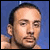Static pixelated image of a person's face with short dark hair against a blue background, rendered in low-resolution 8-bit style.