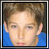 Pixelated image of a person with light brown hair in blue shirt, next to pixelated text and musical note graphic on white background.