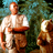 Pixelated static image of a shirtless figure with orange skin and brown pants standing next to a smaller brown animal-like shape against a greenish background.