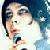 Pixelated close-up of a person with dark hair and light skin holding a microphone, set against a blue-toned background.
