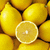 A static image of multiple yellow lemons with one sliced in half, showing the interior and seeds, arranged closely together in a dense composition.