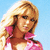 Pixelated image of a person with blonde hair wearing a pink top against a light blue background.