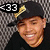 A pixelated image of a person wearing a black cap with gold emblem, smiling against a textured background, accompanied by yellow text on dark and light