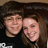 Two people with brown hair smiling closely together in a pixelated image, wearing dark clothing.