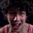 Pixelated image of a person with curly hair and a red striped shirt on a blue background with pink text.
