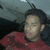 A person in a red shirt with dark patterns sits inside a vehicle, head turned slightly left to right across frames.